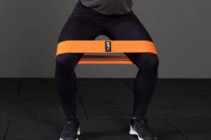 woman using a Mirafit fabric resistance band to perform a squat and tone her legs