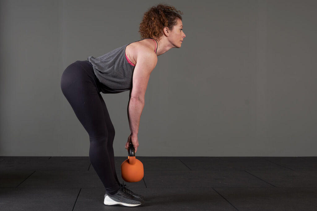 Woman performing a Jefferson Curl with a Mirafit soft touch cast iron kettlebell