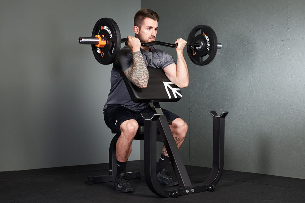 Man performing a preacher curl with a Mirafit Preacher Curl Bench and EZ barbell and weight plates