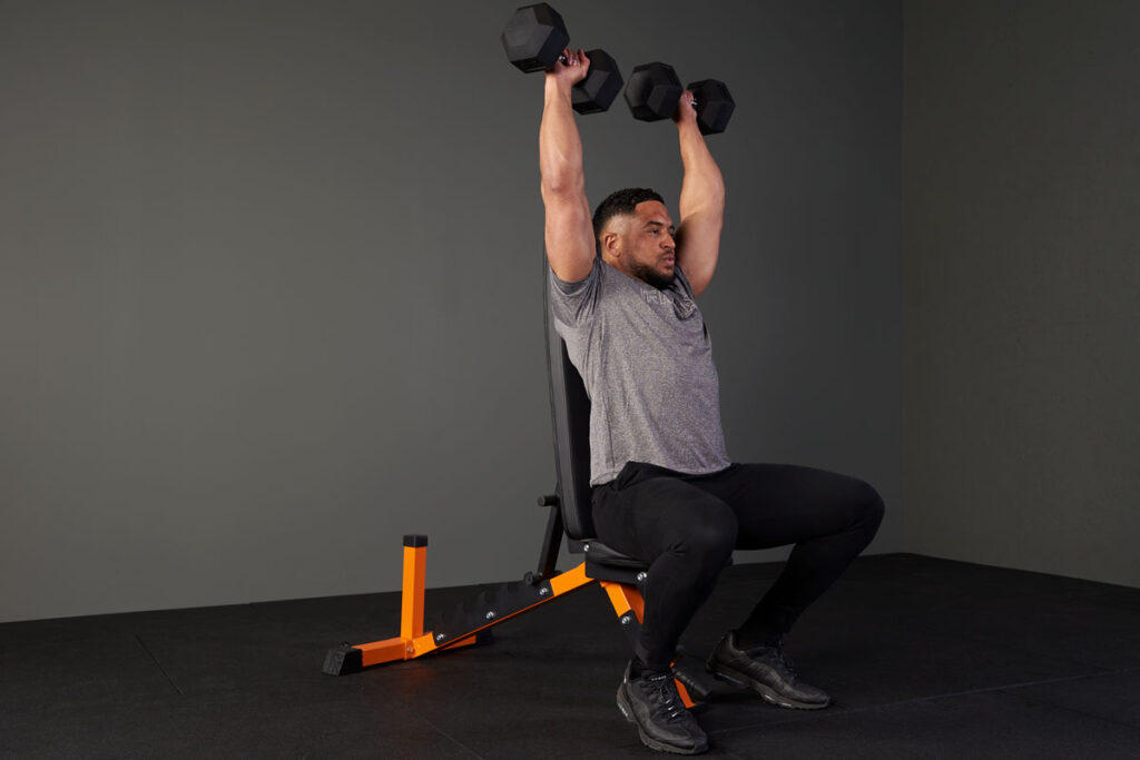 Man performing an incline dumbbell shoulder press with a Mirafit hex dumbbell and adjustable weight bench