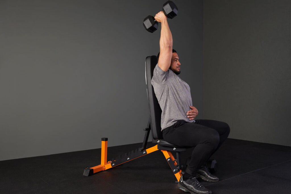 Man performing an overhead dumbbell tricep extension with a Mirafit hex dumbbell and adjustable weight bench