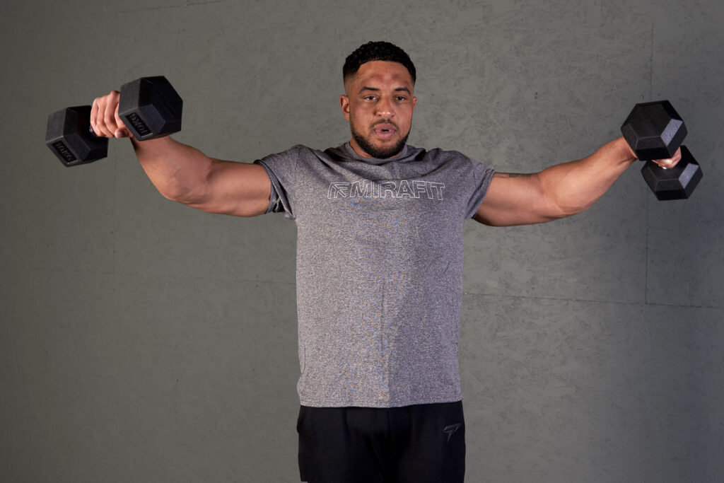Man performing lateral raises using Mirafit hex dumbbells