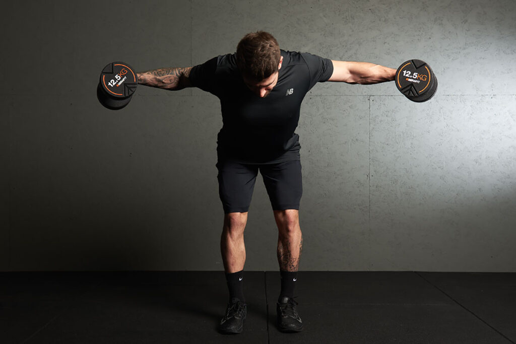 Man performing a dumbbell reverse fly with Mirafit 12.5kg dumbbells.