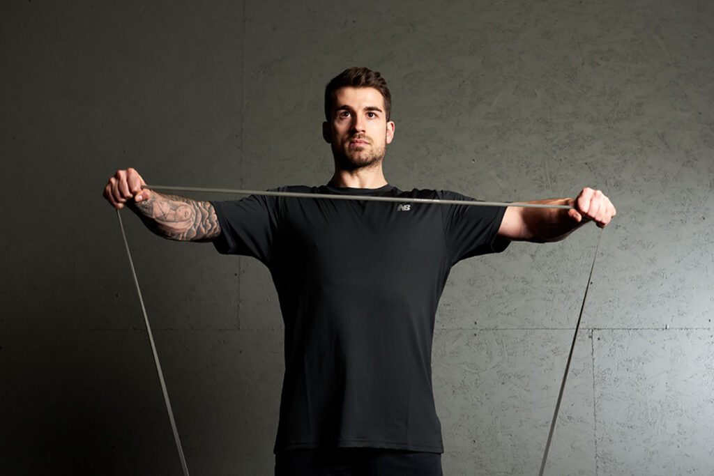 Man performing a resistance band lateral raise with a Mirafit Resistance Band.