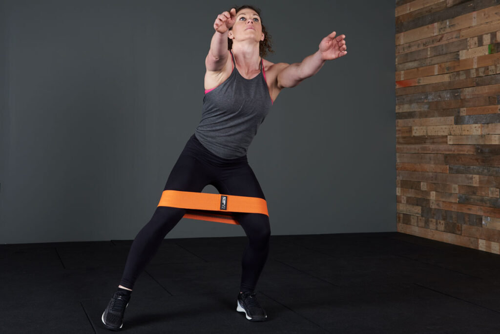 Woman performing a resistance band side step to squat with a Mirafit fabric resistance band.