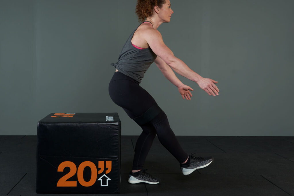 Woman performing a resistance band single leg squat to bench with a Mirafit fabric resistance band.