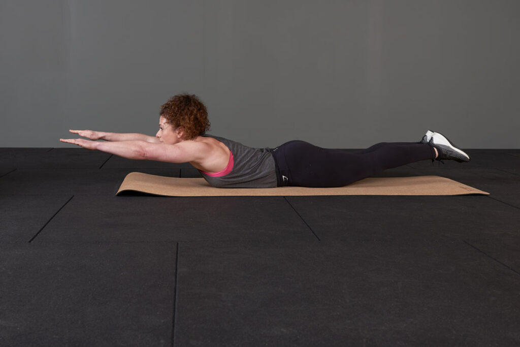 Woman performing superman isometrics with a Mirafit cork 6mm yoga mat.
