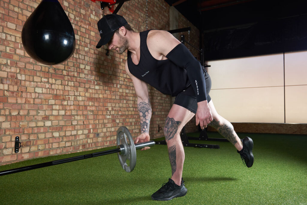 Landmine single leg deadlift Man doing a landmine single leg deadlift with Mirafit cast iron weight plates