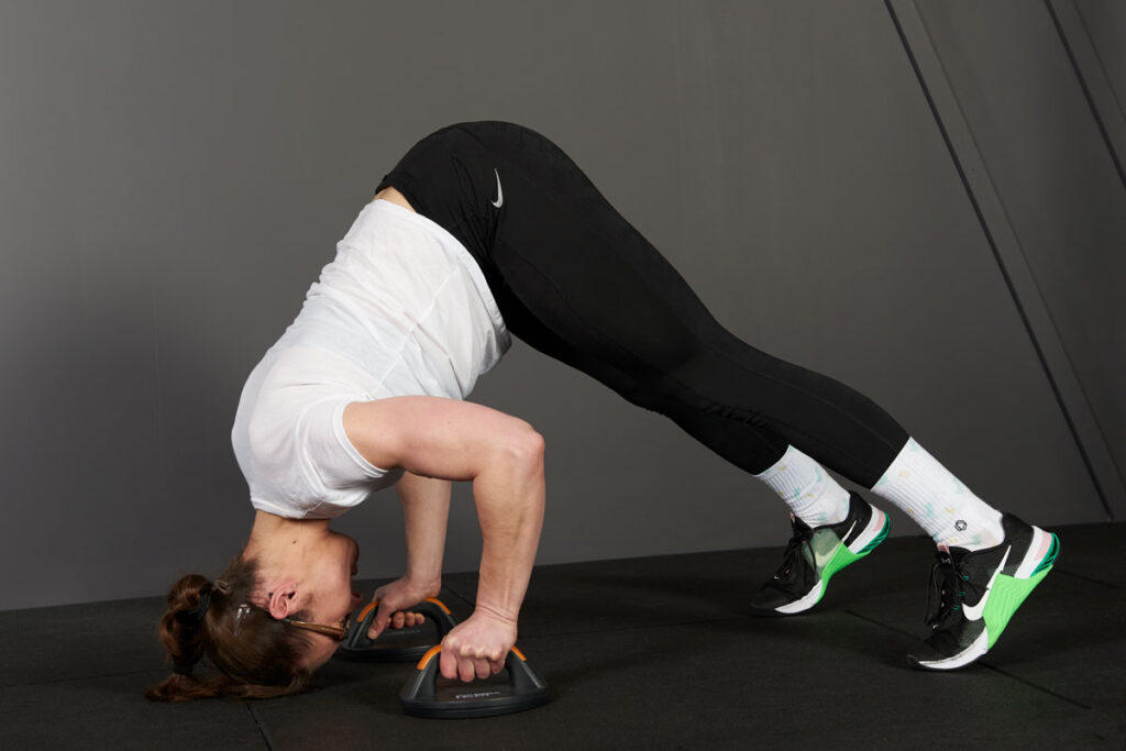 Mirafit Rotating Push Up Bars woman performing a push up bar pike press with Mirafit rotating push up bars