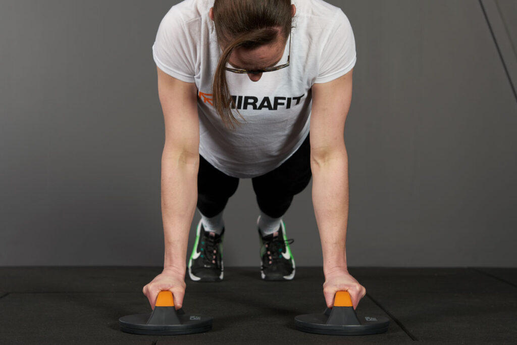 Mirafit Rotating Push Up Bars woman performing a push up with a pair of Mirafit rotating push up bars