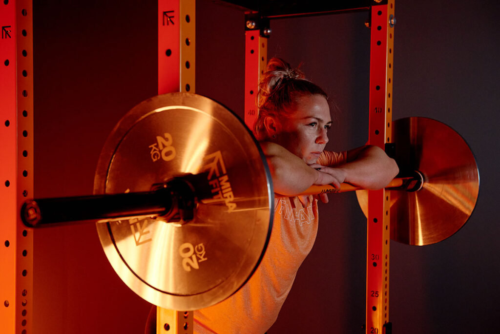 WSM Donna Moore leaning on a Mirafit women's barbell with some 20kg weight plates