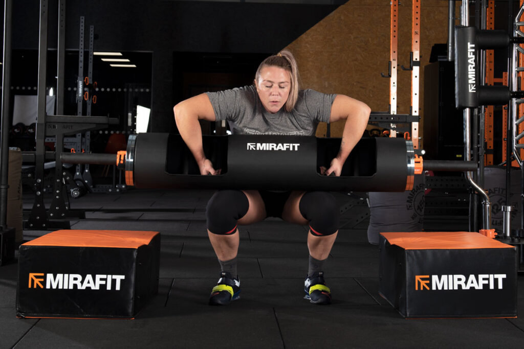 Mirafit Gen II 2" Olympic Weight Bar Quick Release Collars Strongwoman Donna Moore tucking a Mirafit Strongman Log