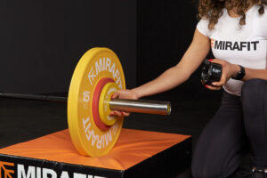 Olympic Weightlifter Noorin Gulam adding Mirafit Olympic Change Plates to a women's barbell
