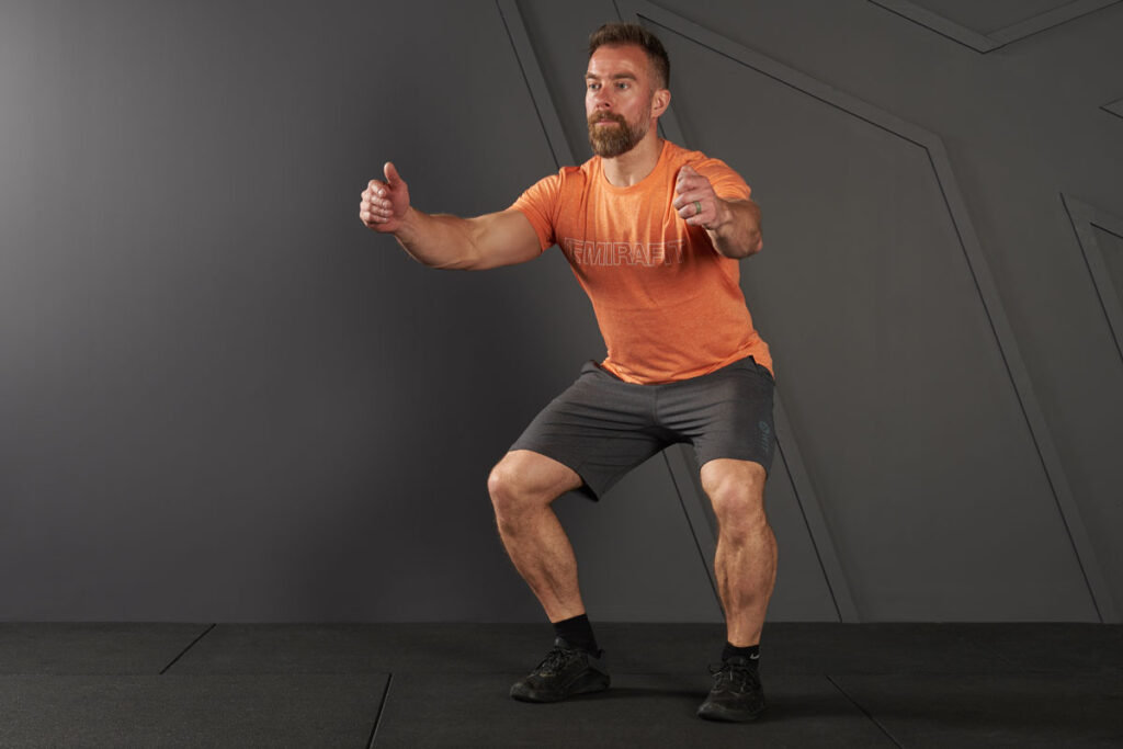 Jump Squat Man doing a jump squat in a Mirafit t-shirt