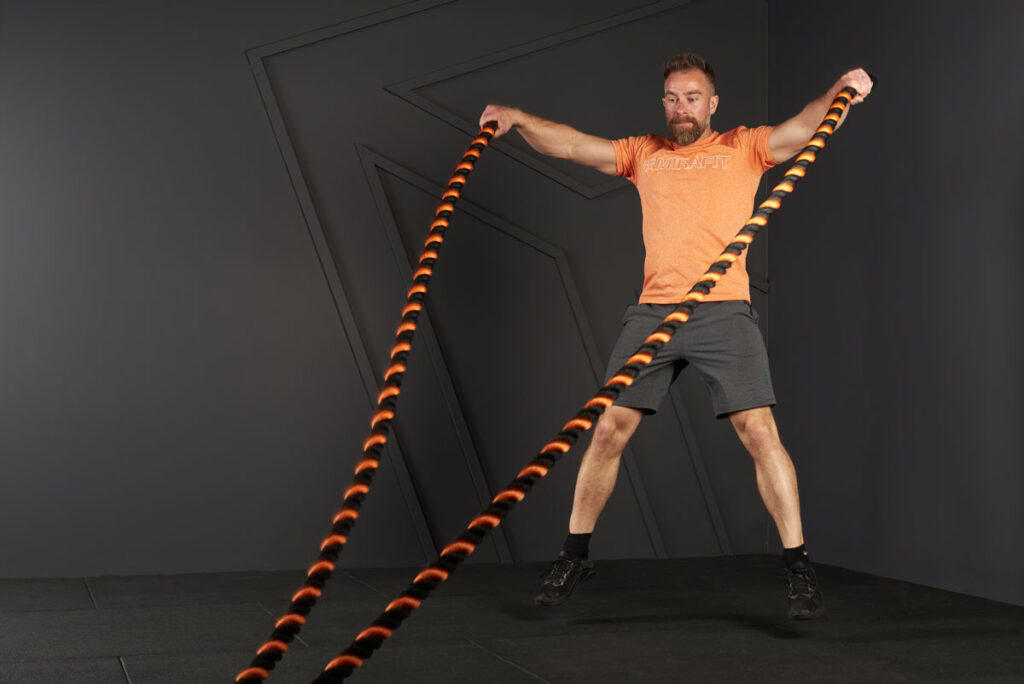 Man doing a jumping jack with a Mirafit Battle Rope