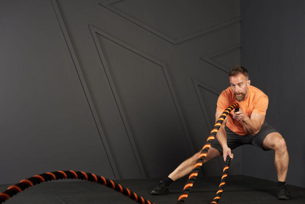 Man doing a lateral lunge with alternating waves with a Mirafit Battle Rope