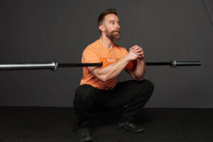 Man doing a zercher squat with a Mirafit Olympic barbell