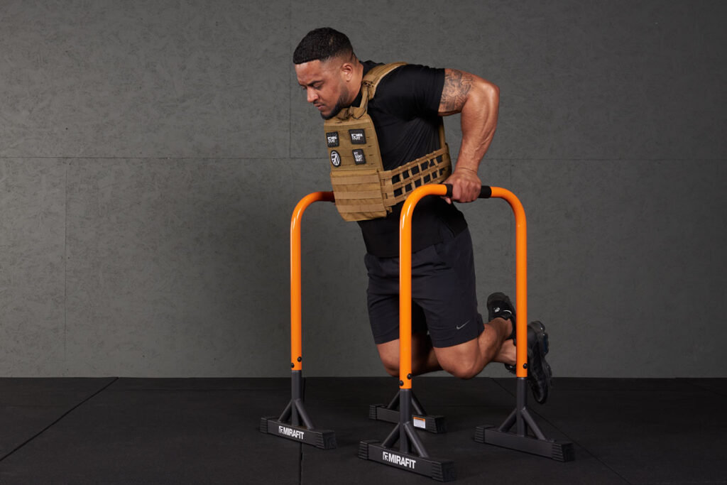 Tricep dips Man doing tricep dips with a Mirafit Tactical Weight Vest and dip bars