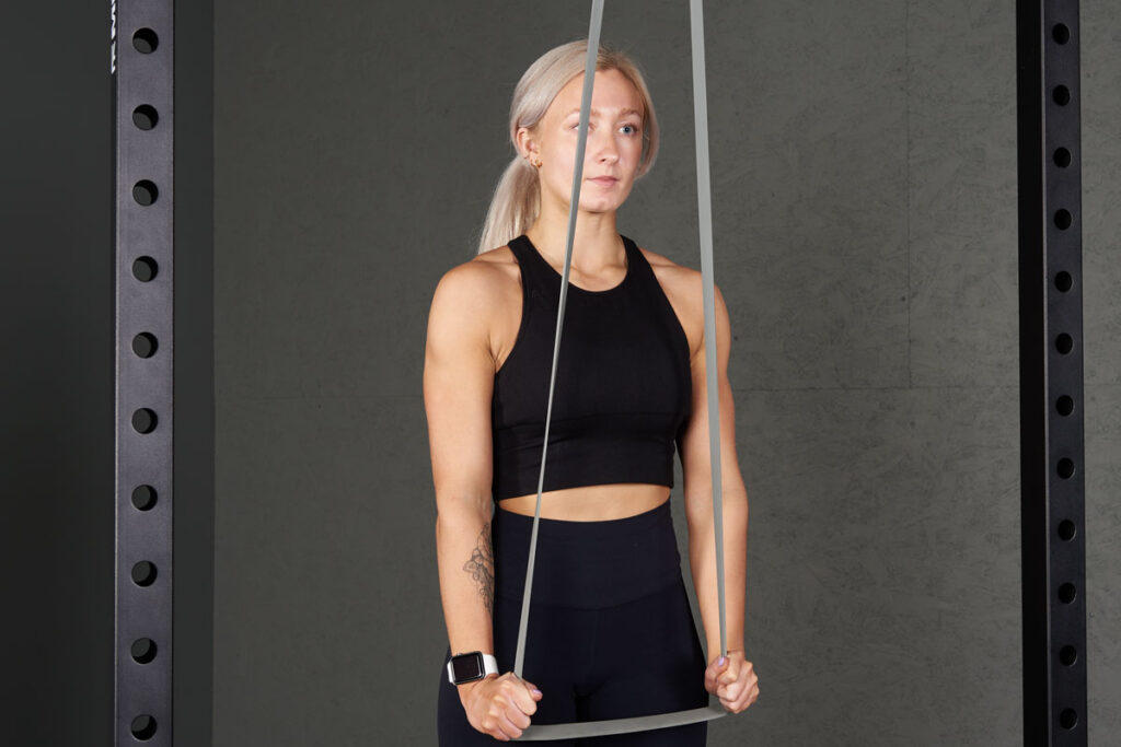 Banded Tricep Push Down Woman doing a banded tricep push down with a Mirafit Resistance Band