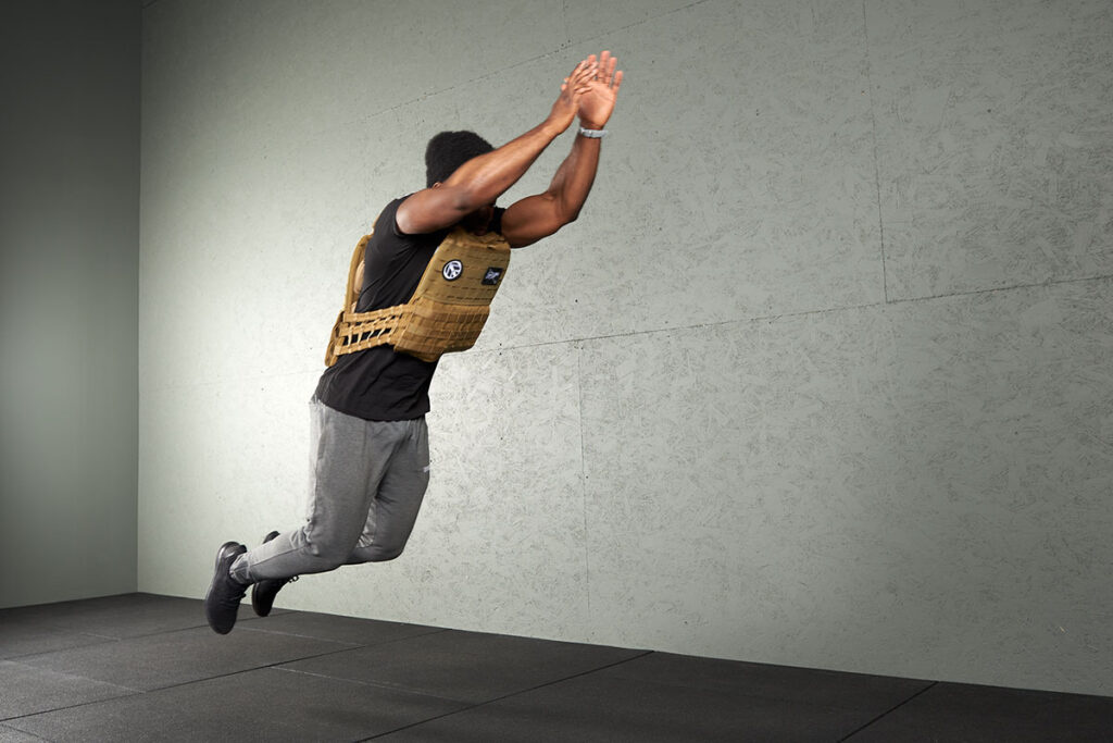 Man doing a broad jump with a Mirafit Tactical Weight Vest