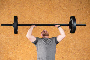 Strongman Adam Bishop overhead pressing a Mirafit Axle Bar