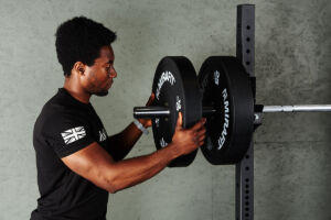 Man loading Mirafit bumper plates onto an Olympic Barbell