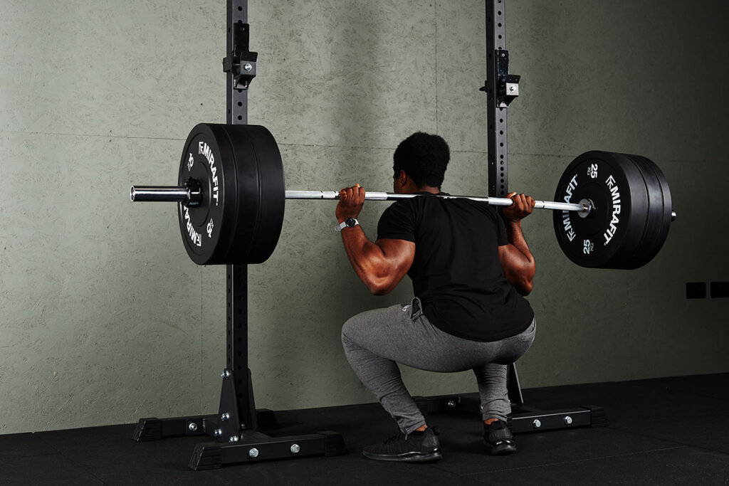 Man squatting with Mirafit Bumper Plates during a drop set