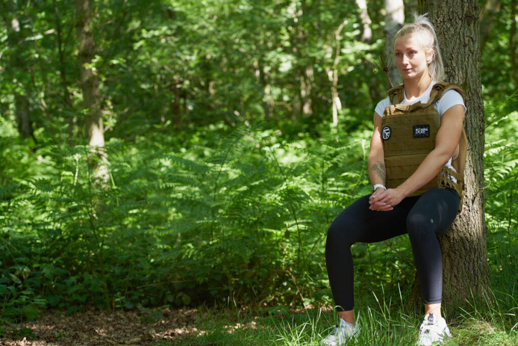 Wall Sit Woman doing a wall sit in a Mirafit Tactical Weight Vest