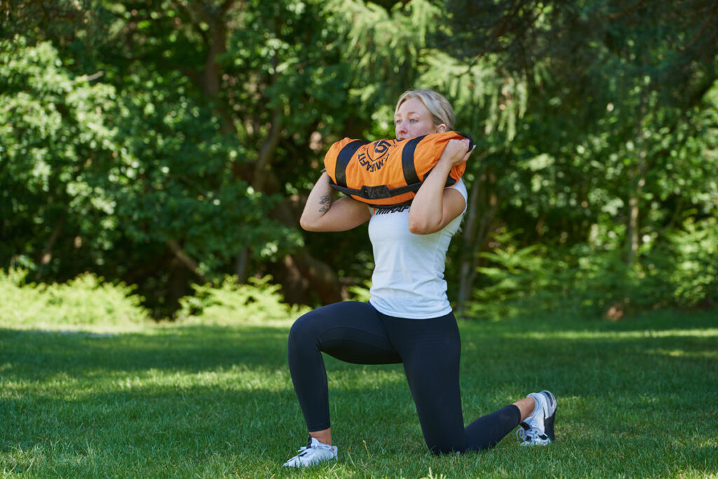 Woman doing a forward lunge with a Mirafit Gym Sandbag