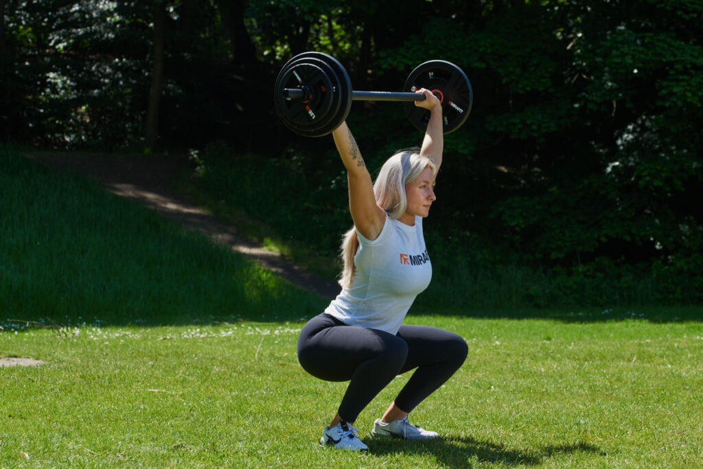 Overhead Squat Woman doing an overhead squat with a Mirafit Studio Pump Set