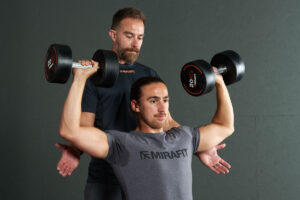 Man being spotted during a dumbbell seated bench press - 20kg dumbbells