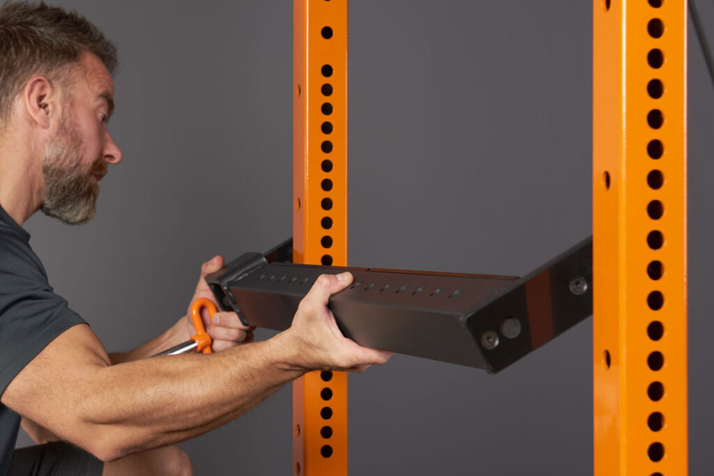 Man attaching a spotter bar to a Mirafit Power Rack