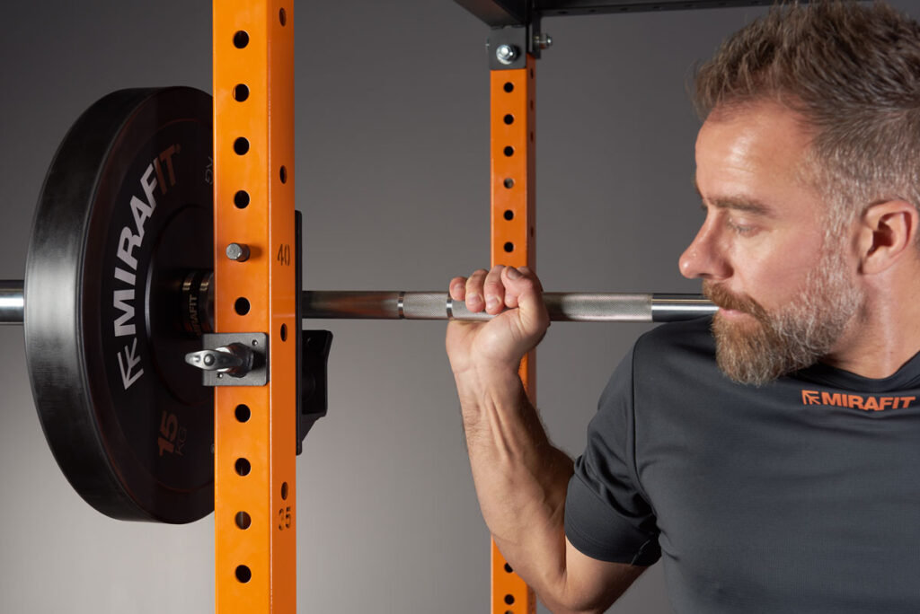 Man squatting with a Mirafit Olympic Barbell