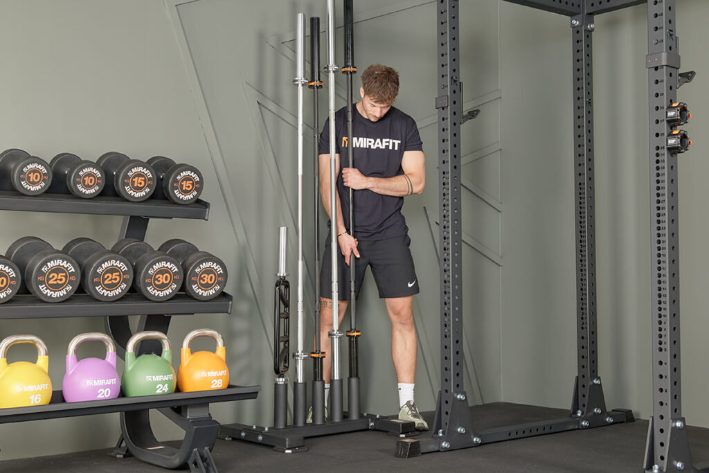 Mirafit Commercial Series Barbell Holder Man unloading a barbell from a Mirafit Commercial Series Barbell Holder