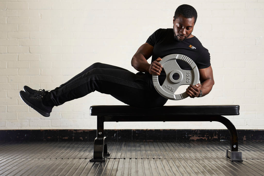 Man doing a Russian Twist with a tri-grip 10kg weight plate