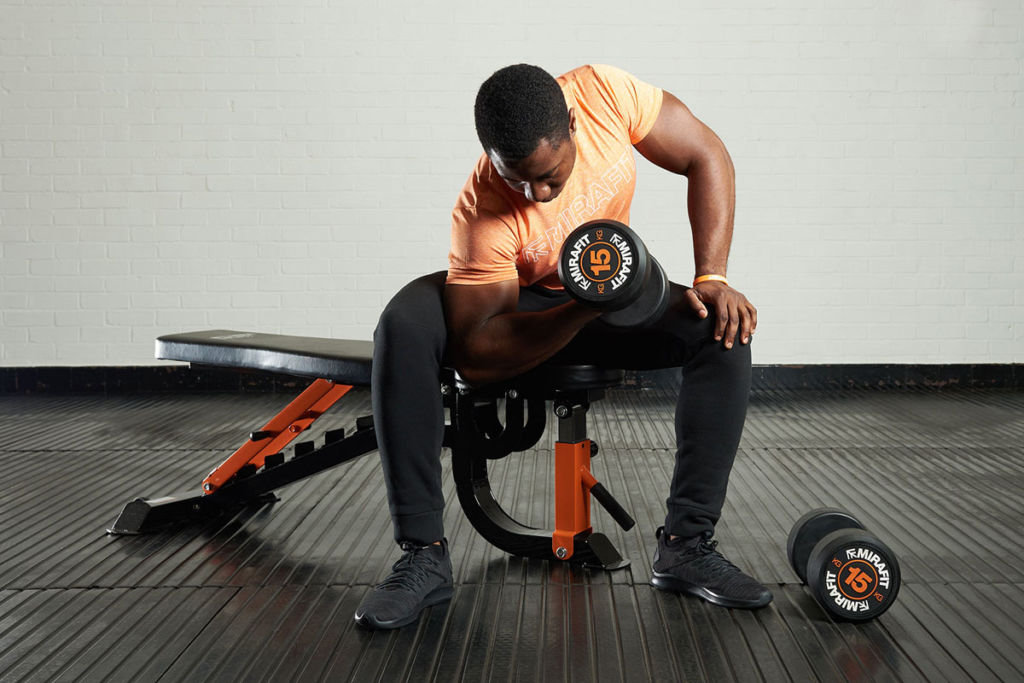 Man doing concentration curls with Mirafit 15kg dumbbells