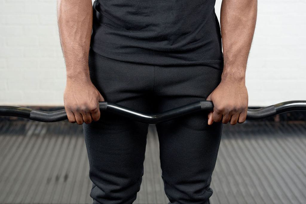 Standard overhand grip Man performing a standard overhand grip on a Mirafit EZ Curl Bar