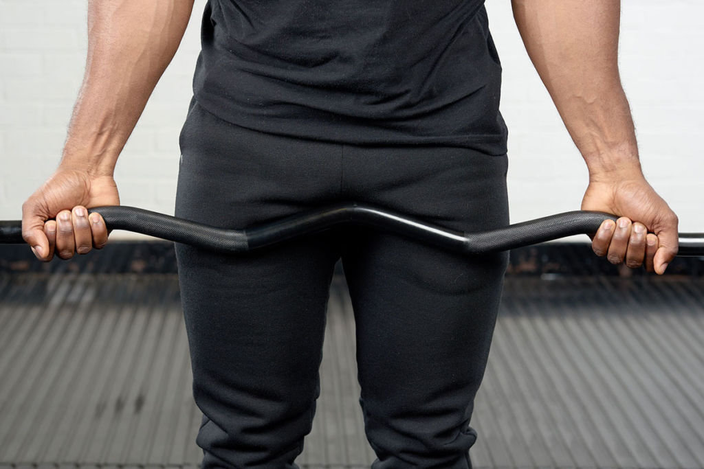 Wide underhand grip Man performing a wide underhand grip on a Mirafit EZ Curl Bar