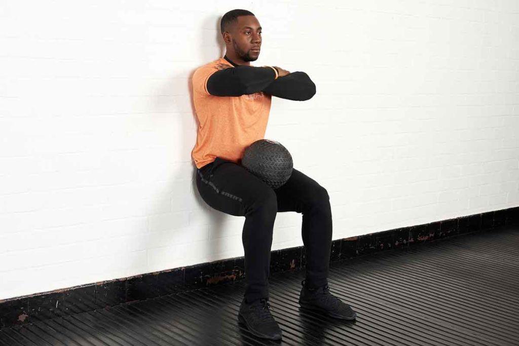 Wall sit Man doing a wall sit with a Mirafit Tyre Tread Slam Ball