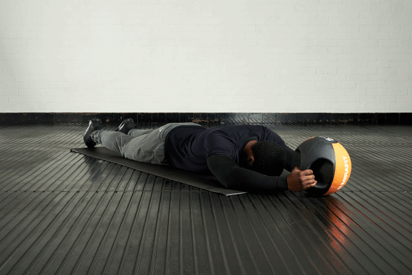 Weighted superman Man demonstrating the weighted superman exercise with a Mirafit double handle medicine ball