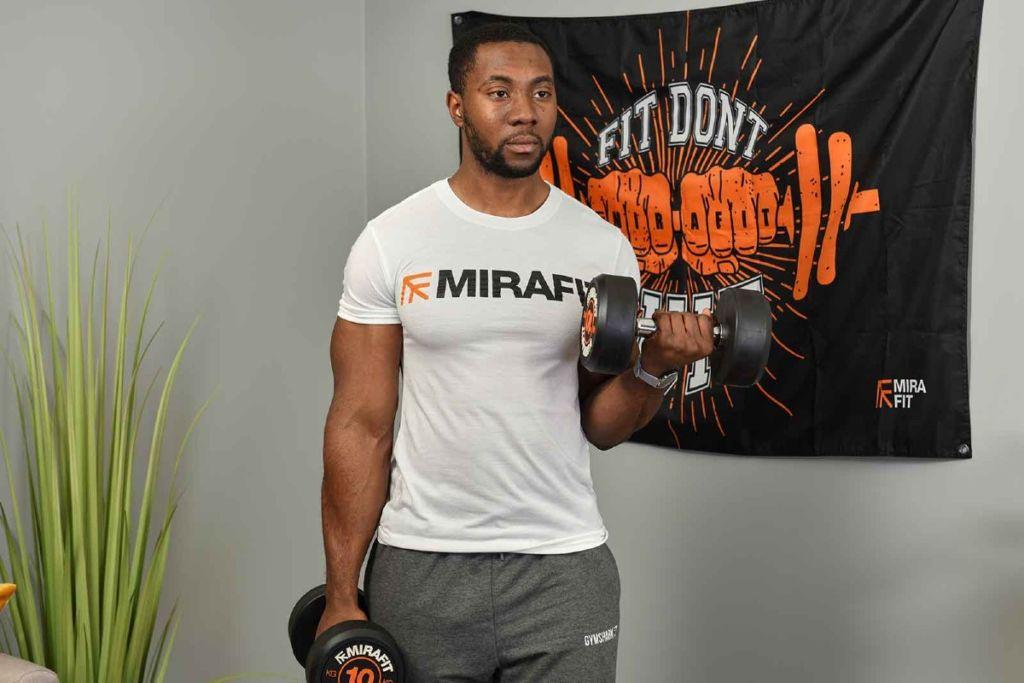 This is an image of a fitness model demonstrating the bicep curl exercise in his living room. 