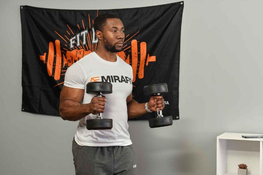 This is an image of a fitness model demonstrating the hammer curl exercise in his living room. 