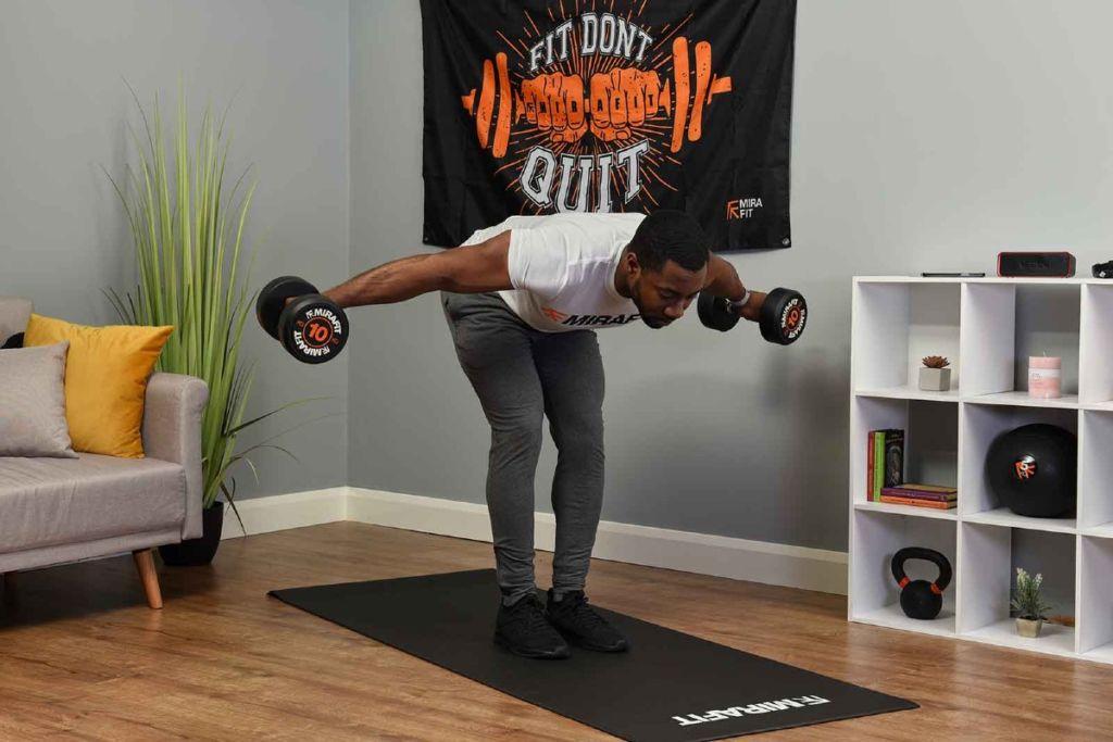 This is an image of a fitness model demonstrating the reverse fly exercise in his living room. 