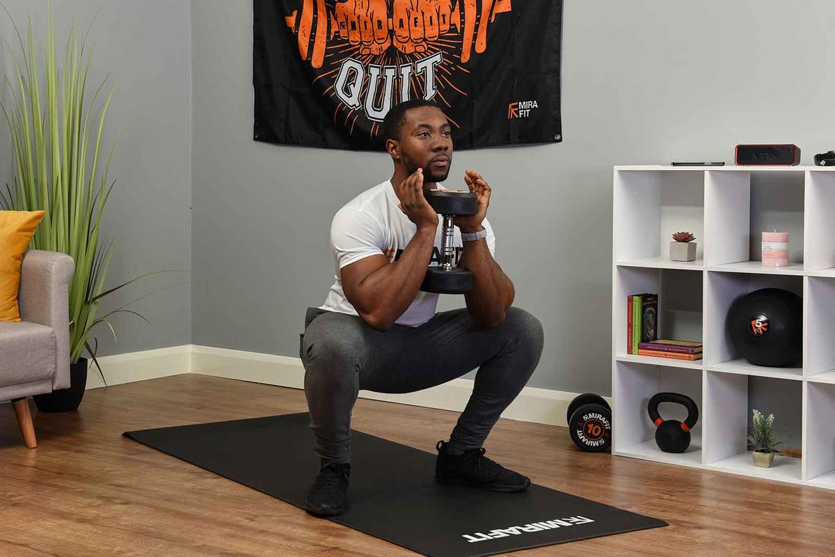 fitness model demonstrating the dumbbell squat exercise with just one dumbbell. The exercise can be performed with two.